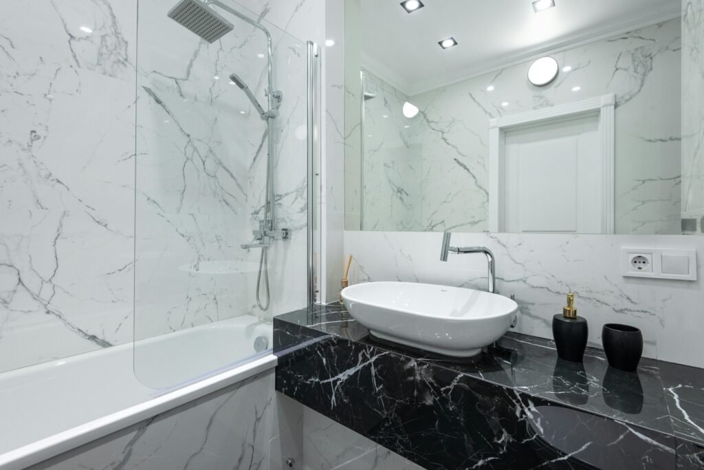 Luxurious bathroom featuring marble walls, a vessel sink, and contemporary fixtures.